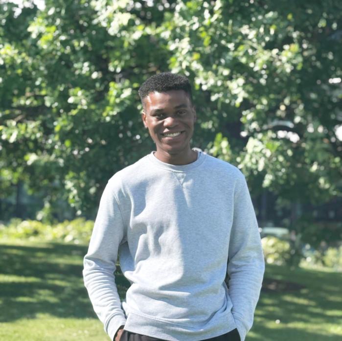 A student standing in front of greenery.